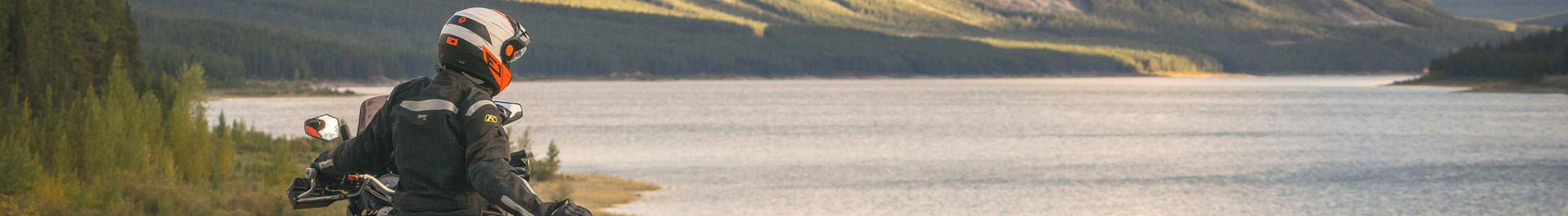 Ein Motorradfahrer bei sonnigem Wetter an einem See